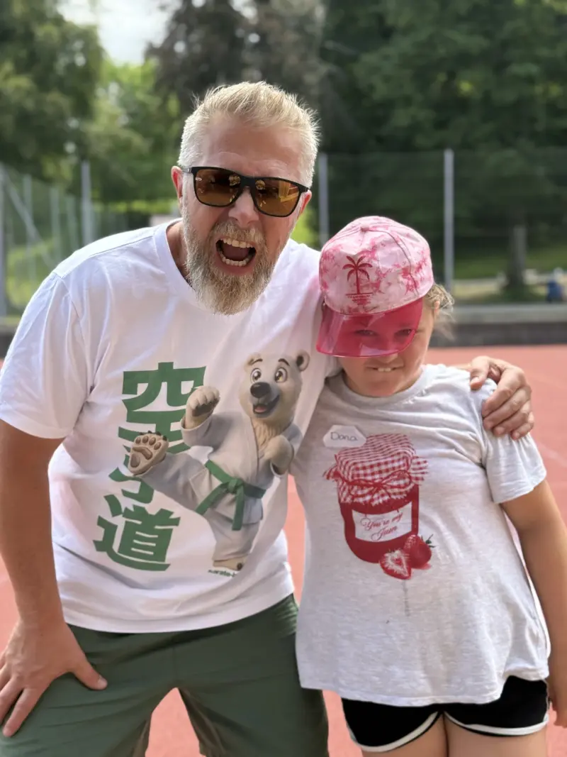 Mann und Kind posieren lachend im Freien