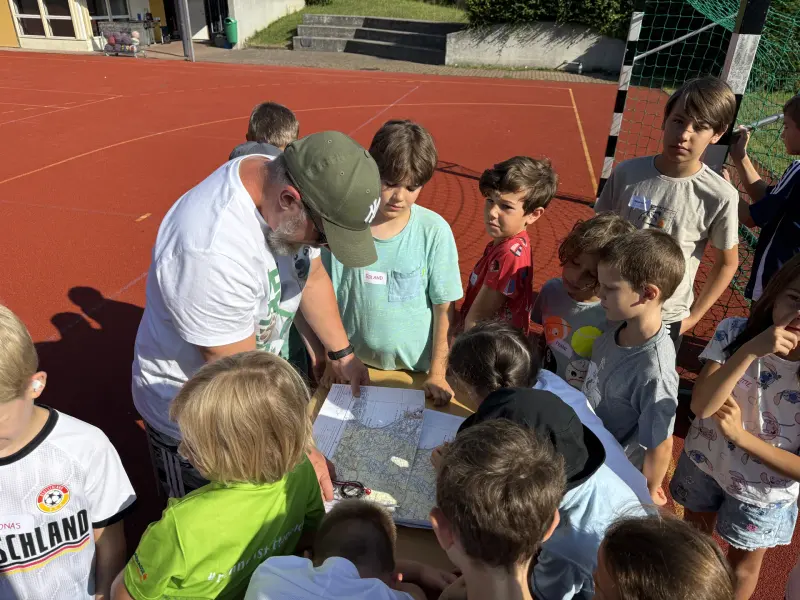 Gruppe von Kindern betrachtet mit Betreuer eine Landkarte