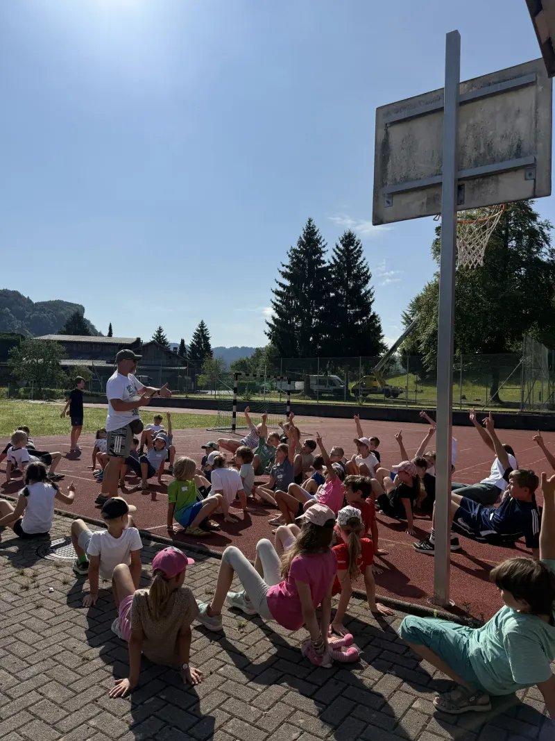 Gruppe von Kindern stützt sich im Freien am Boden ab