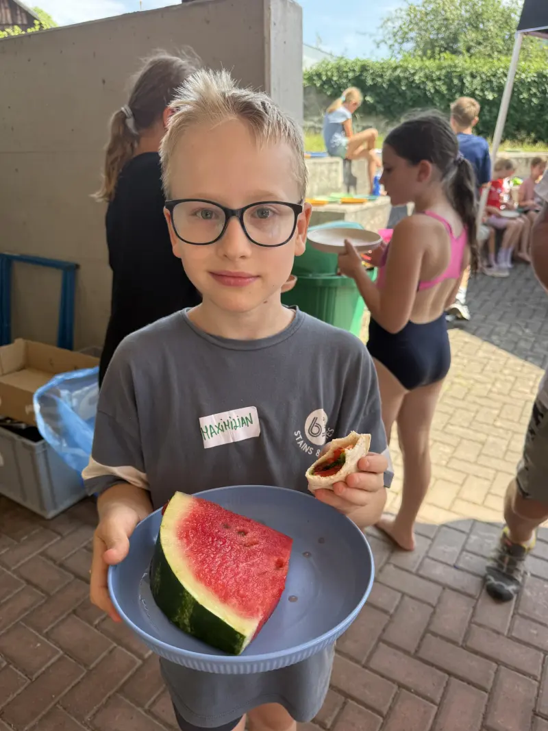 Kind hält Schüssel mit Wassermelone und gefülltem Wrap