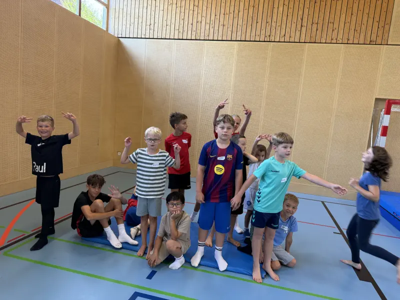 Gruppe von Kindern posiert ausgelassen in der Sporthalle