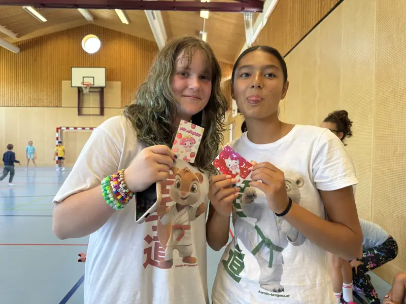 Zwei Kinder zeigen ihre Sammelkarten in der Sporthalle