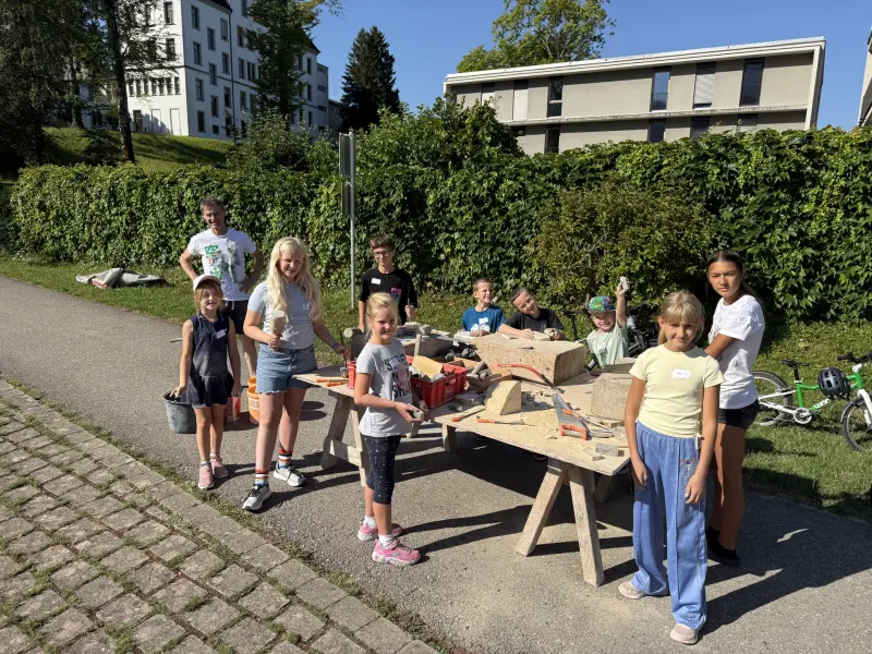 Kinder versammeln sich am Werktisch zur Steinbearbeitung