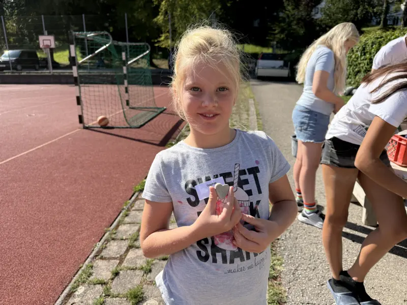 Kind zeigt ein bemaltes Herz aus Stein