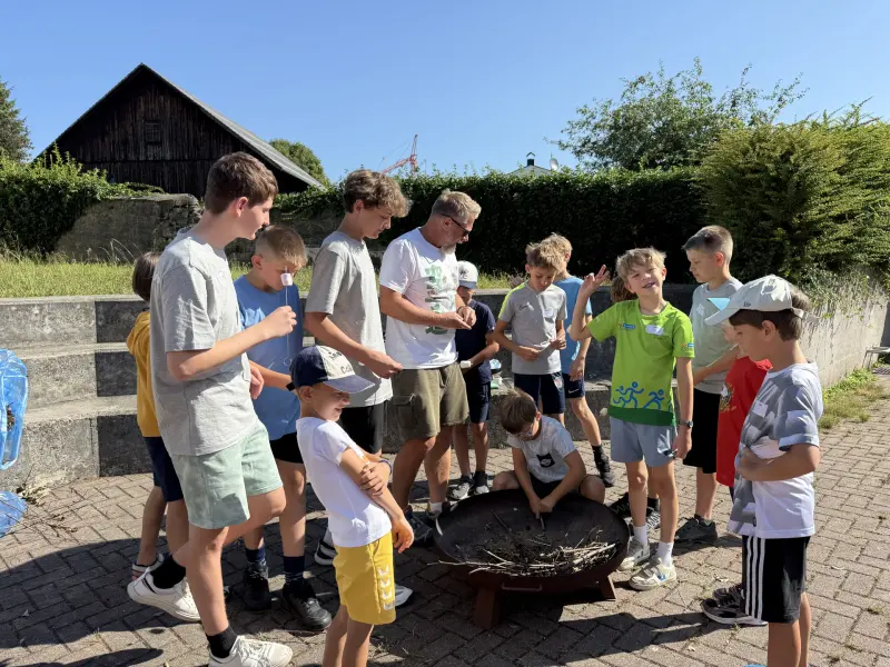 Kinder versammeln sich um eine Feuerschale im Freien