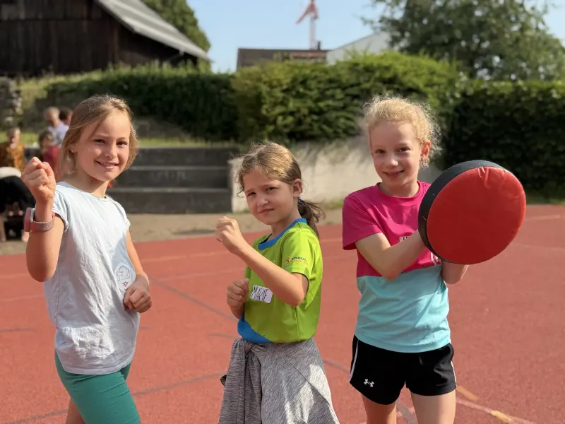 Drei Kinder posieren mit erhobenen Fäusten und Schlagpolster