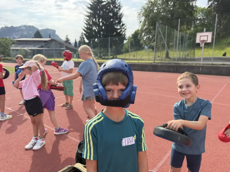 Kind mit blauem Kopfschutz auf dem Sportplatz