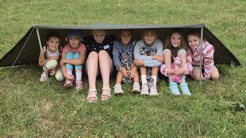 Gruppe von Kindern sitzt im selbstgebauten Unterschlupf