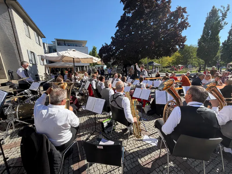 Musikkapelle spielt bei Sonnenschein vor Publikum an Biertischen